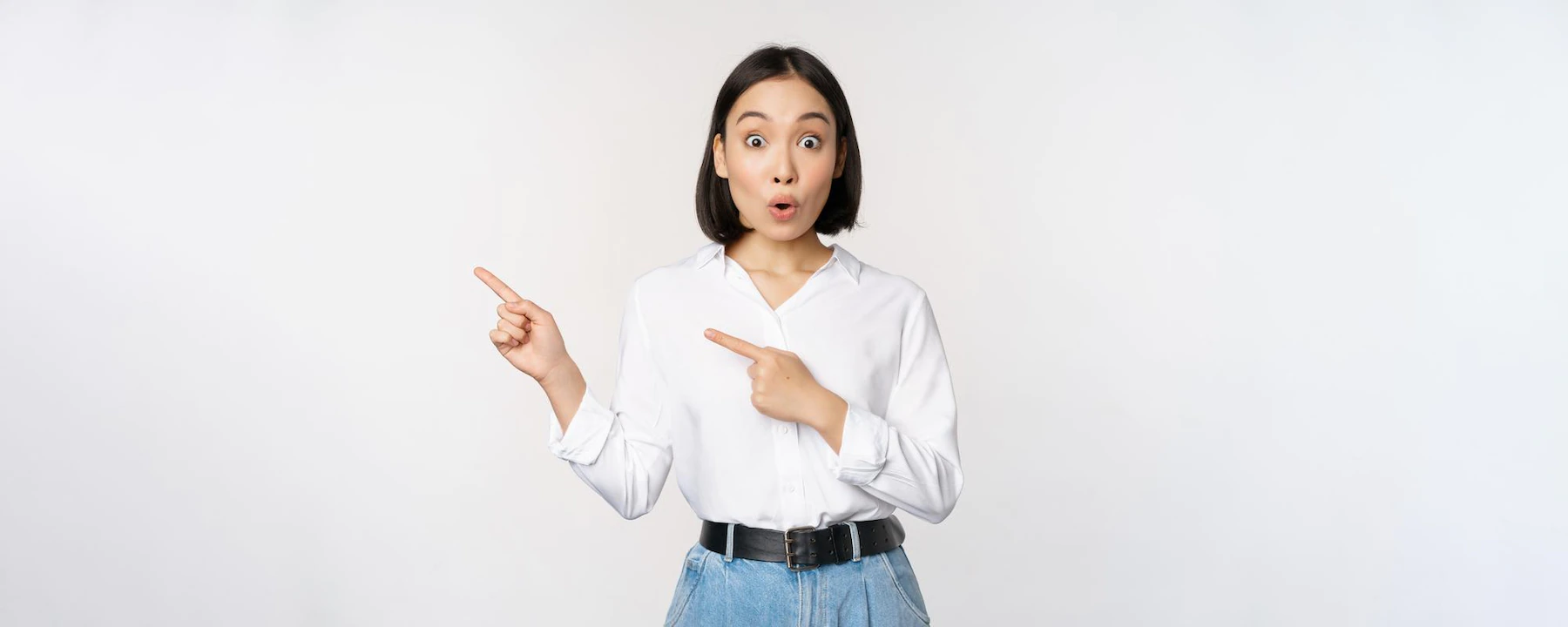 portrait of excited young asian woman office lady pointing fingers left at discount showing sale banner standing over white background 1258 98640