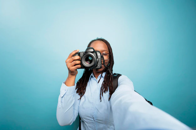 young adult african american woman pointing dslr device camera while taking photo blue background creative amateur photographer taking pictures with modern camera social media 482257 49054