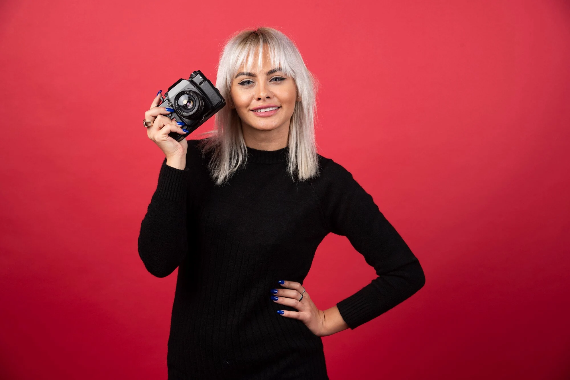 beautiful young woman holding camera while standing against red background high quality photo 114579 60838
