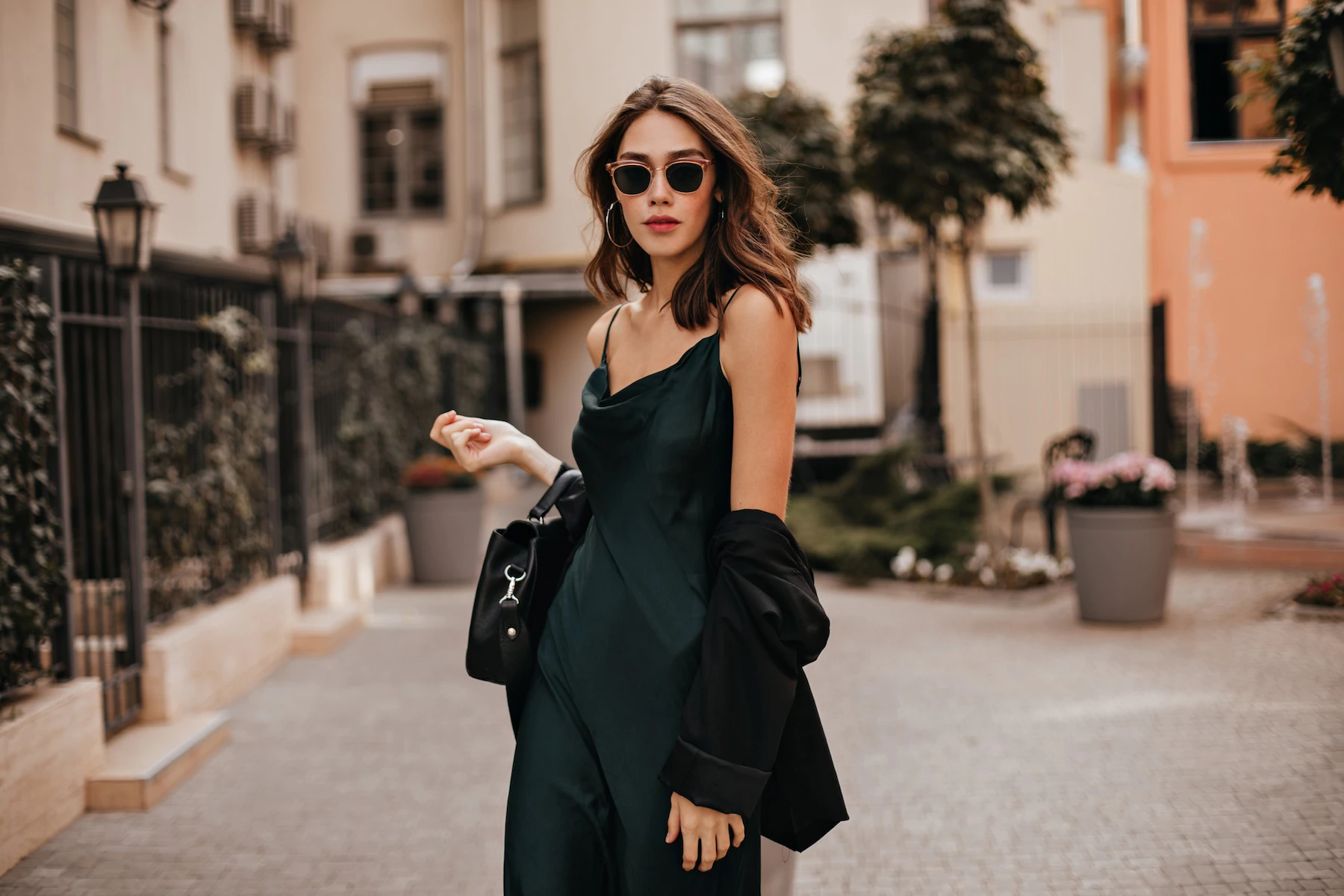 fashionable pale brunette long green dress black jacket sunglasses standing street during daytime against wall light city building 197531 24468
